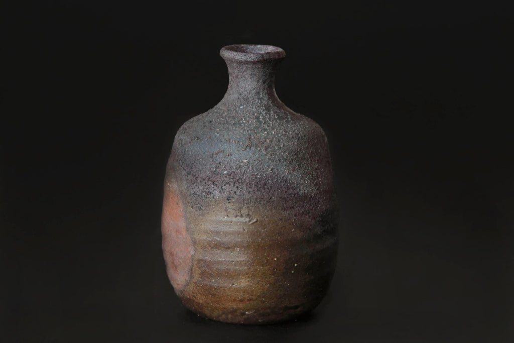 Bizen ware sake tokkuri bottle with natural ash glaze and
rough surface texture, showing fire marks and earthy tones.