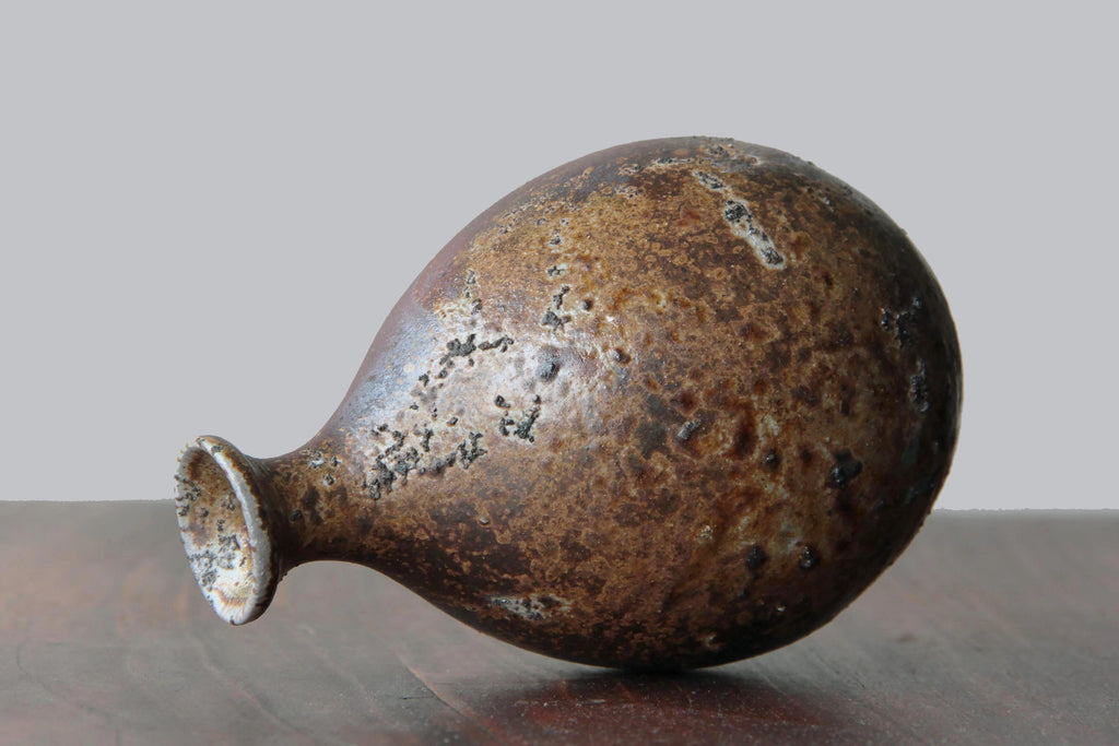 Bizen ware sake bottle with a rounded body and narrow neck, featuring natural kiln firing marks and earthy brown tones.