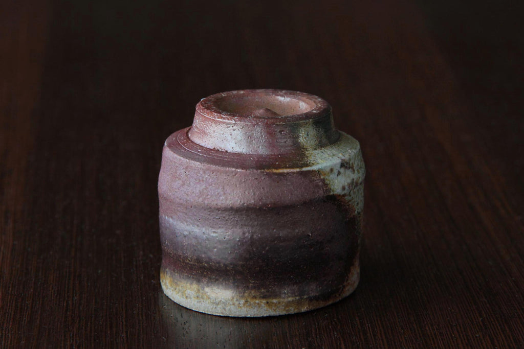 Bizen ware sake cup placed upside down, showing the circular foot and reddish-brown natural firing patterns.