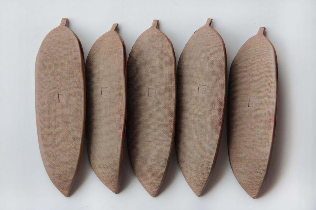 Bottom view of Echizen-yaki bamboo leaf plates, unglazed textured clay surface with kiln mark
stamp in the center.
