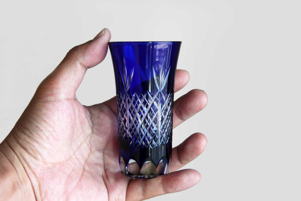 Edo Kiriko glass held in hand, showing its scale and clarity of blue crystal.