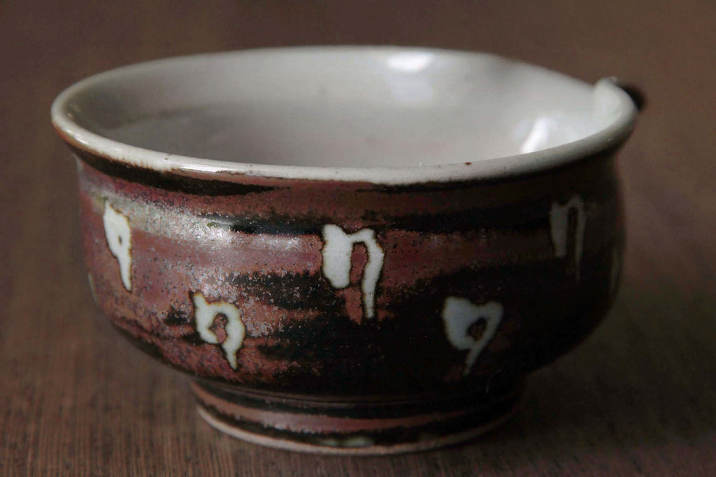 Side close-up of a Yusamashi spouted
bowl with white interior and
reddish-brown exterior with unique drip
patterns