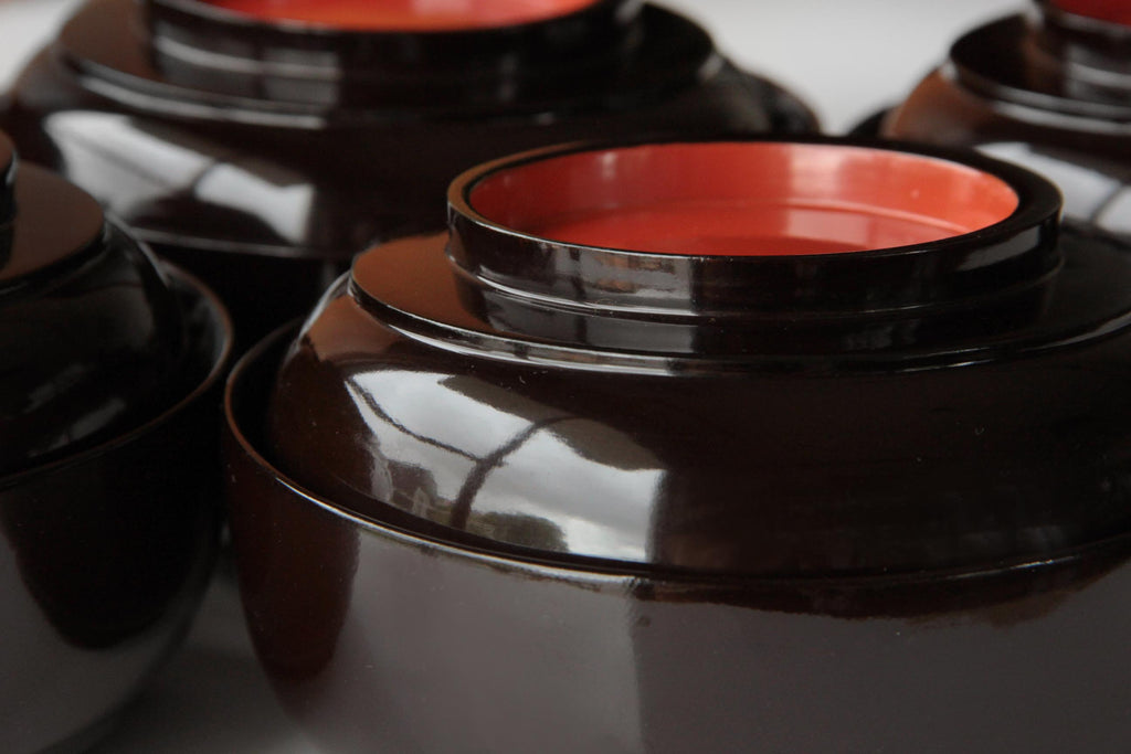 Vintage urushi lacquer soup bowls with glossy black outer surface and deep red interior.
