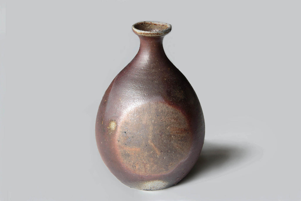 Traditional Bizen ware Tokkuri sake bottle featuring rustic textures and natural ash glaze patterns from wood firing