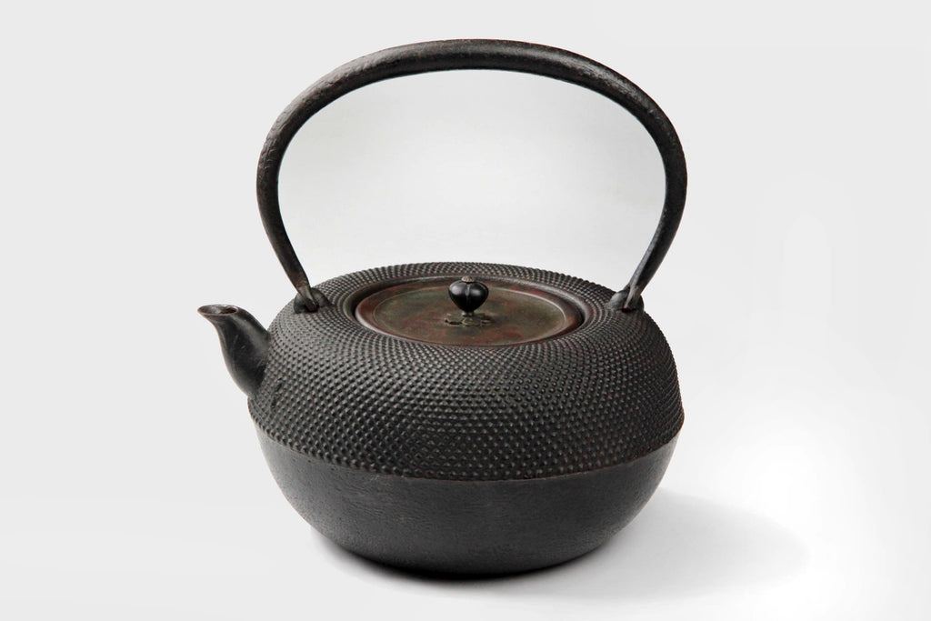Angled top view of a Japanese Tetsubin kettle with a copper lid.