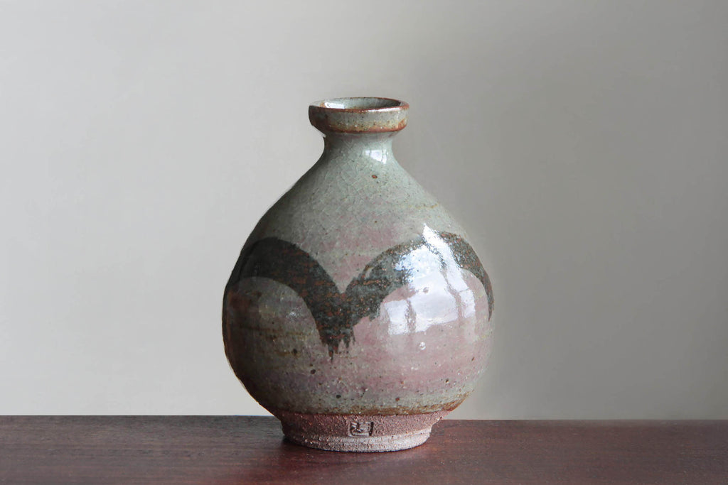 Japanese Sake bottle by a noted potter. Standing on the table.