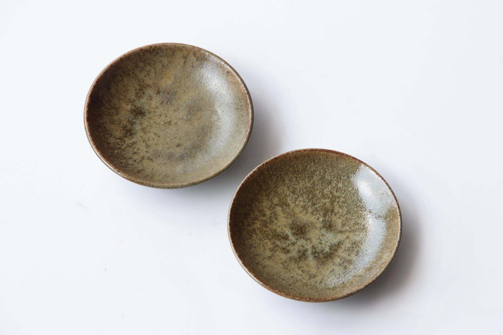 Pair of small Japanese ceramic dishes with earthy green-brown glaze and subtle speckled surface, viewed from above.