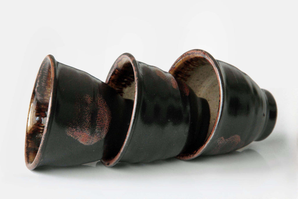 Three Satsuma ware yunomi cups stacked horizontally, highlighting their conical shape and
glossy finish