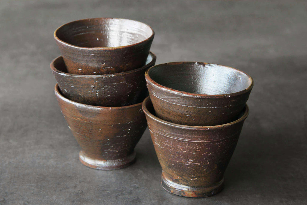 Stacked Japanese tea cups, dark brown
surface with subtle sheen.