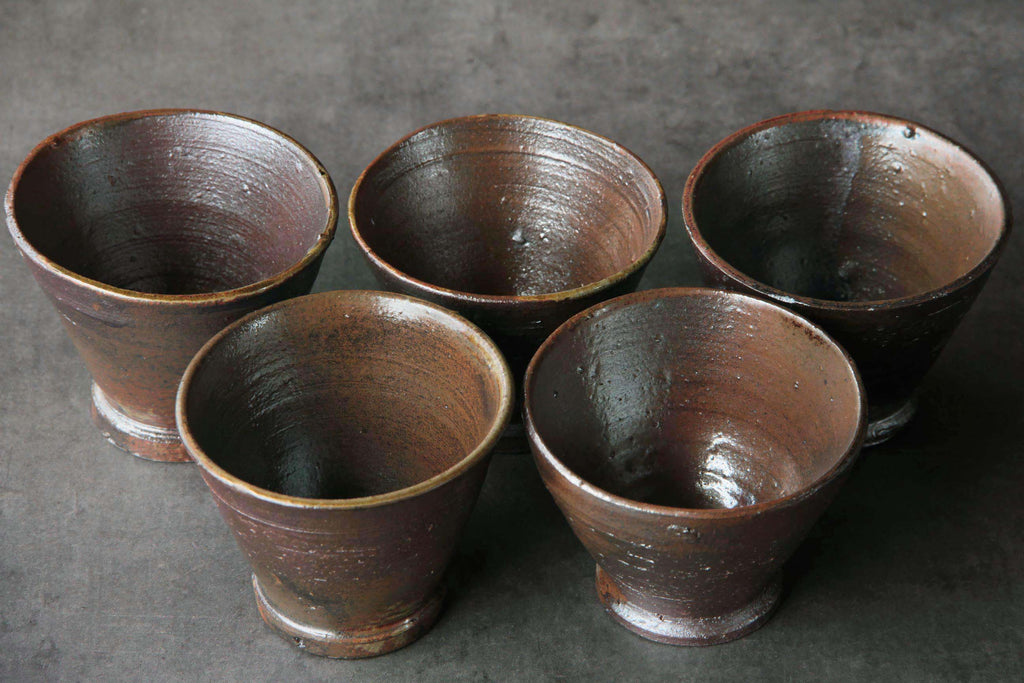Five Kanayama ware cups viewed from above, rustic firing
marks and uneven circular forms.