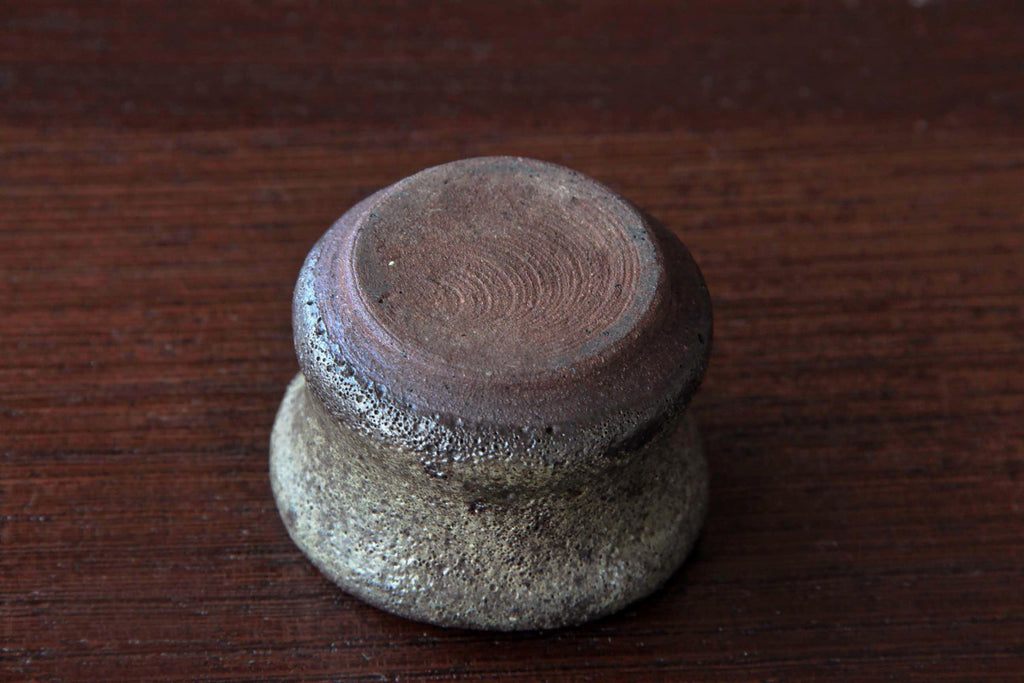 Bottom view of a handcrafted Bizen ware sake cup, showing the unglazed clay base with circular potter’s wheel marks and rustic texture.