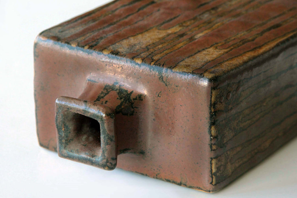 Close up of kaki glaze pottery showing vertical streaks of natural ash and iron melt