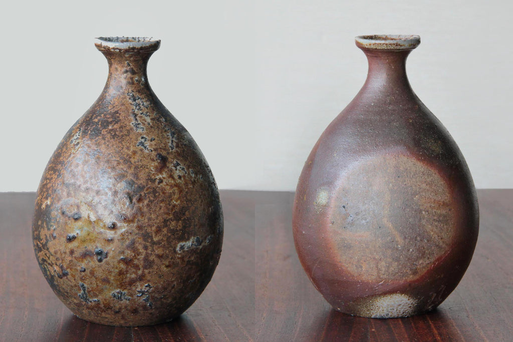 Two Bizen ware sake bottles with natural unglazed surfaces, showing contrasting kiln effects and rustic textures, displayed side by side on a wooden table