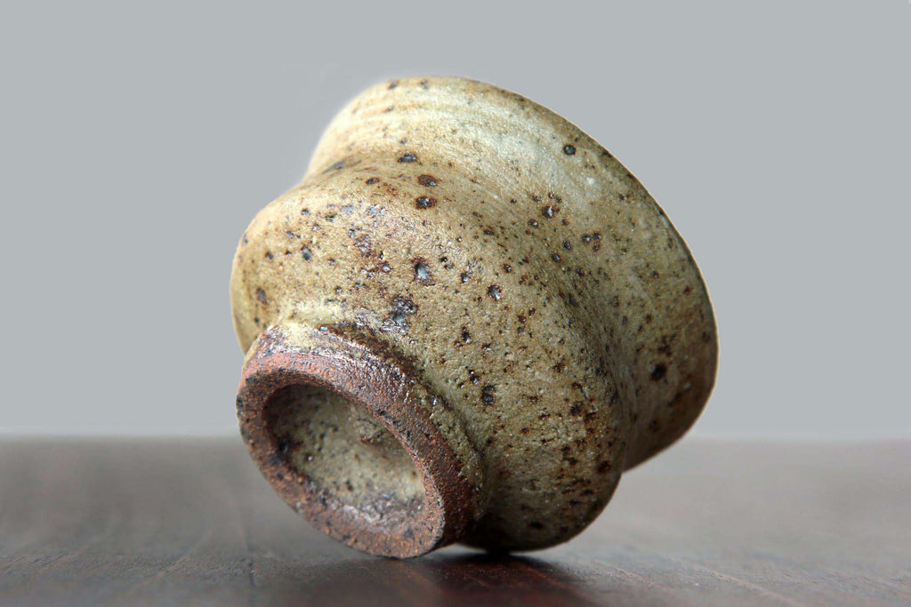 Close-up angled view of a sake cup placed on its side,
showing rough clay base.