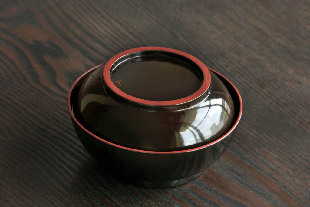 Handcrafted urushi lacquerware lidded bowl with rich natural sheen and vermilion rim detail