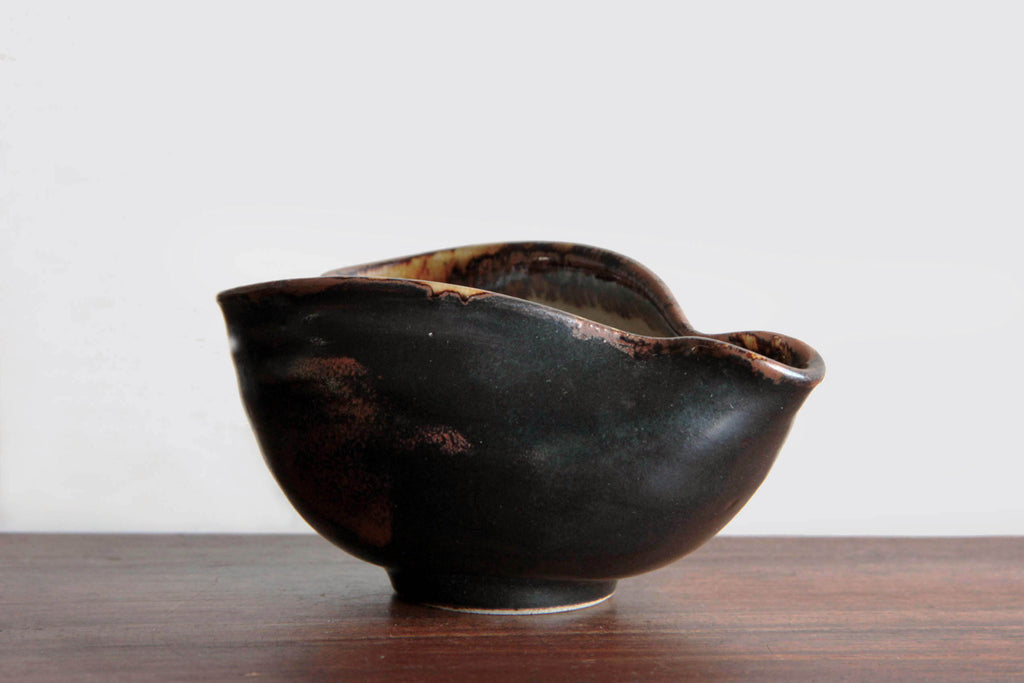 Profile view of the yuzamashi highlighting the smooth black glaze and reddish tones