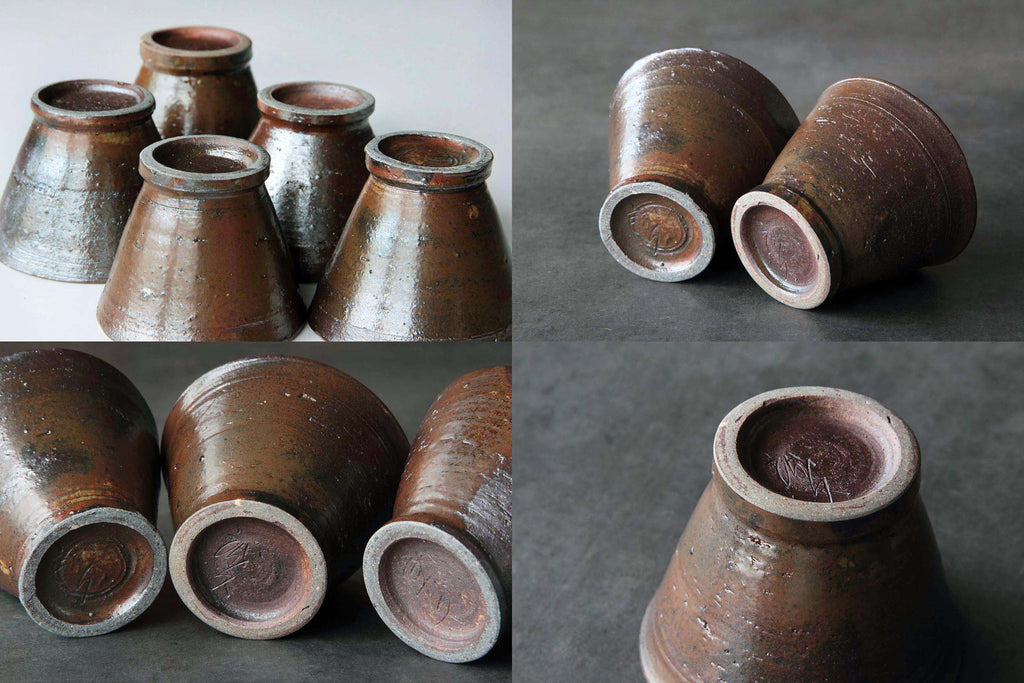 Set of brown Japanese pottery cups turned upside down,
showing kiln marks and potter’s seal.