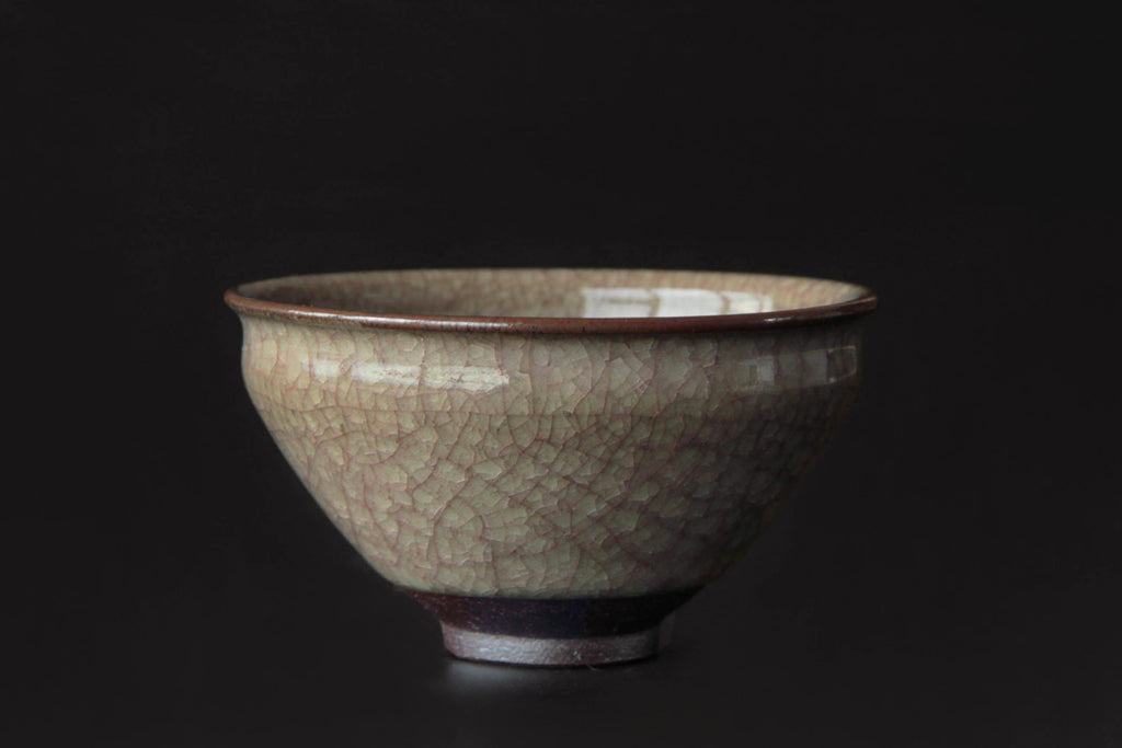 Single yunomi tea cup on dark background highlighting fine crackle glaze texture