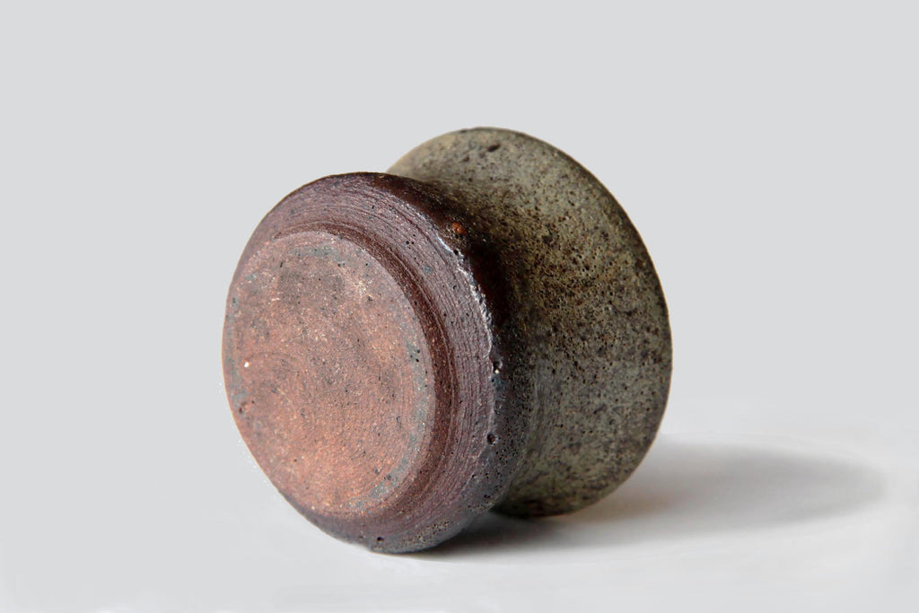 Bottom view of a Bizen ware sake cup highlighting the unglazed base and reddish clay