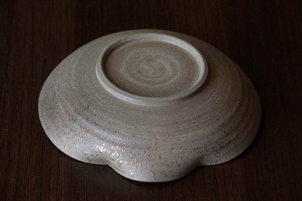Underside view of a Japanese pottery bowl with textured foot and natural ash glaze patterns