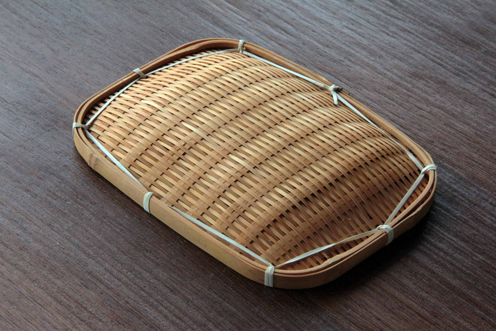 Back view of a rectangular bamboo tray highlighting the natural weave and bindings on a wooden
surface