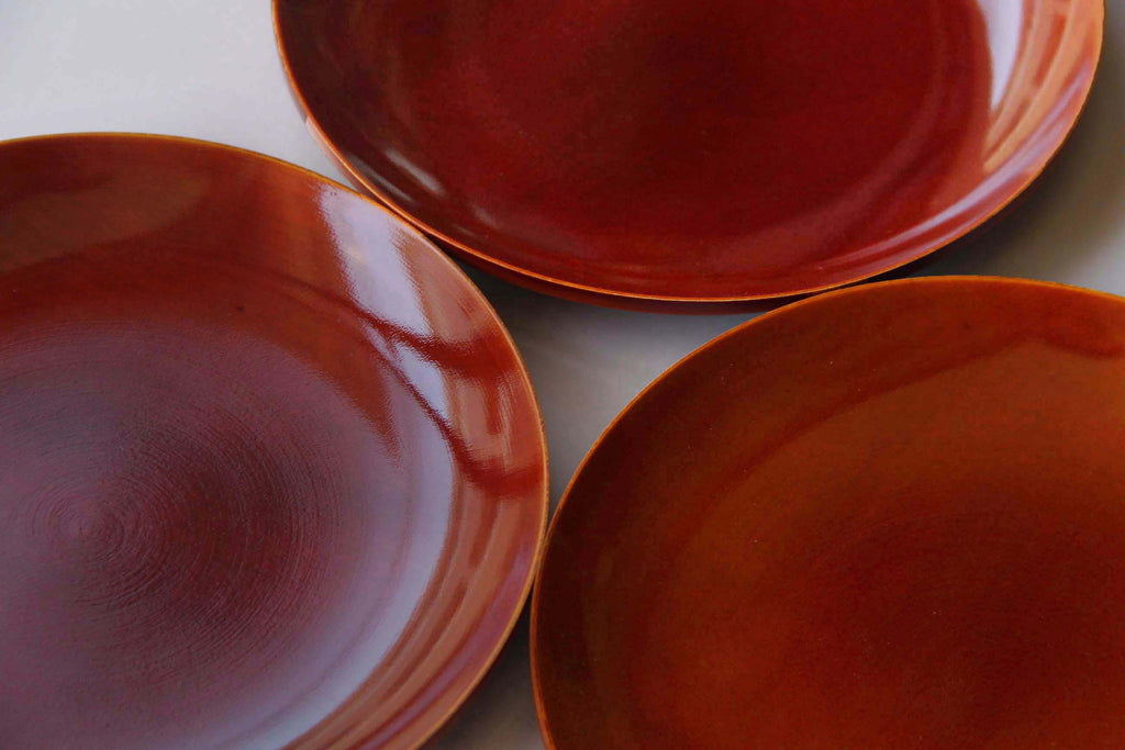 Close-up of three Hida Shunkei lacquerware plates to show subtle wood grain patterns
beneath the translucent lacquer
