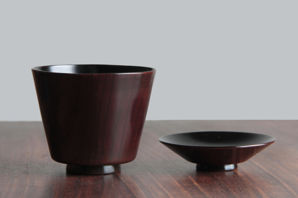 Lacquerware cup and lid displayed separately on a wooden table, showing interior and exterior.
