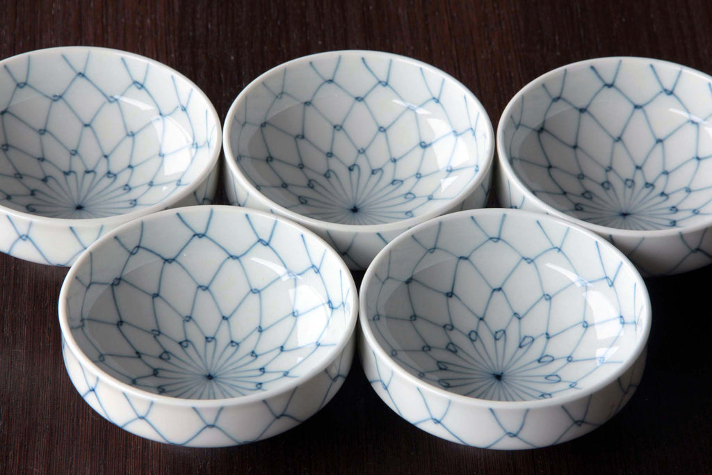 Group of five bowls displayed upright on wooden surface showing interior net pattern design