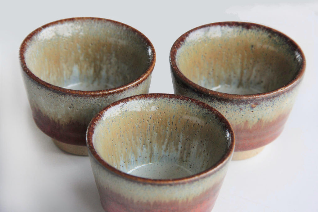 Three rustic Japanese sake cups with dripped glaze detail.