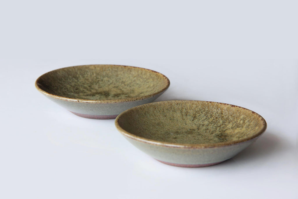 Pair of small Japanese pottery dishes with green-brown ash glaze and speckled interior surface.