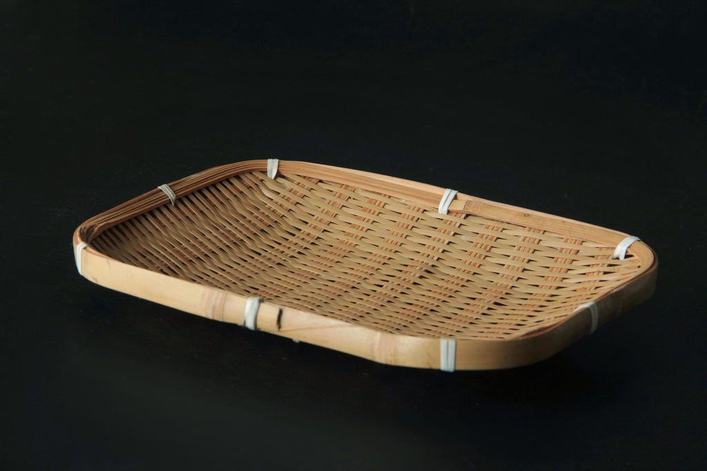 Single rectangular bamboo tray on black background angled to display inner weave and frame
details