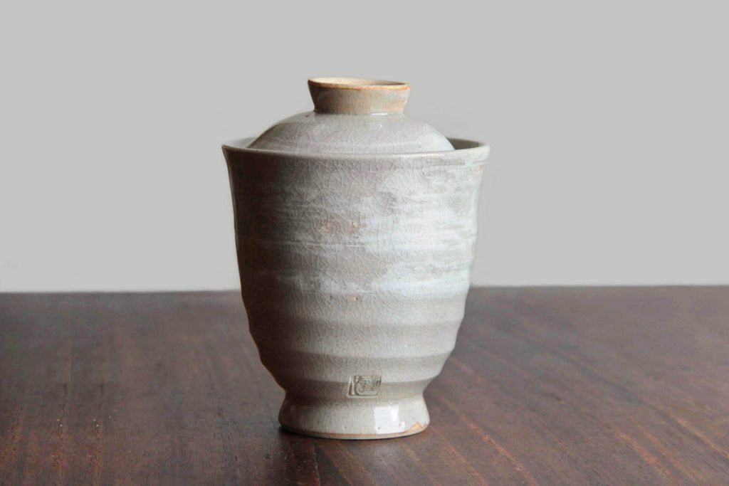 Single lidded tea cup with slightly flared rim and visible kiln mark.